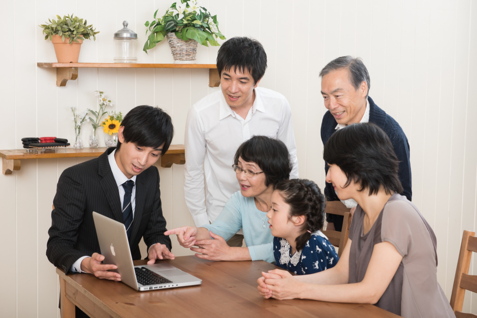 男性司法書士に相談する祖父母・両親・幼い娘の写真